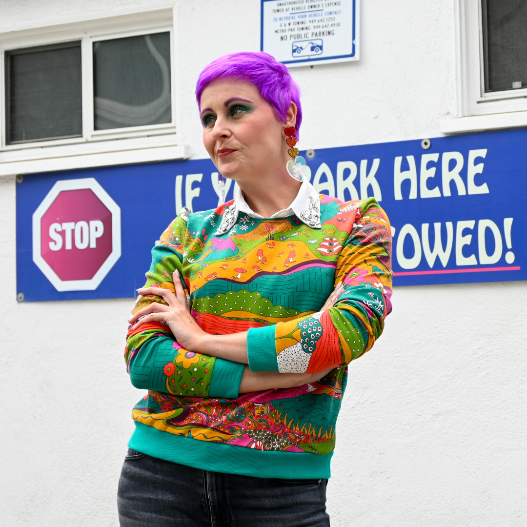 Pretty purple haired model in bright colored printed sweatshirt and black pants