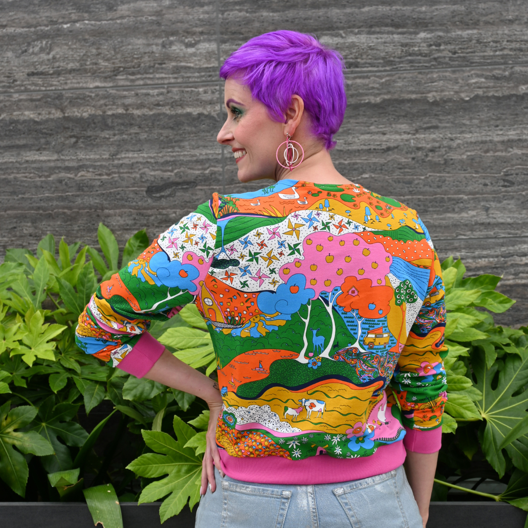 Purple-haired model in rainbow printed sweatshirt and jeans, closeup back view