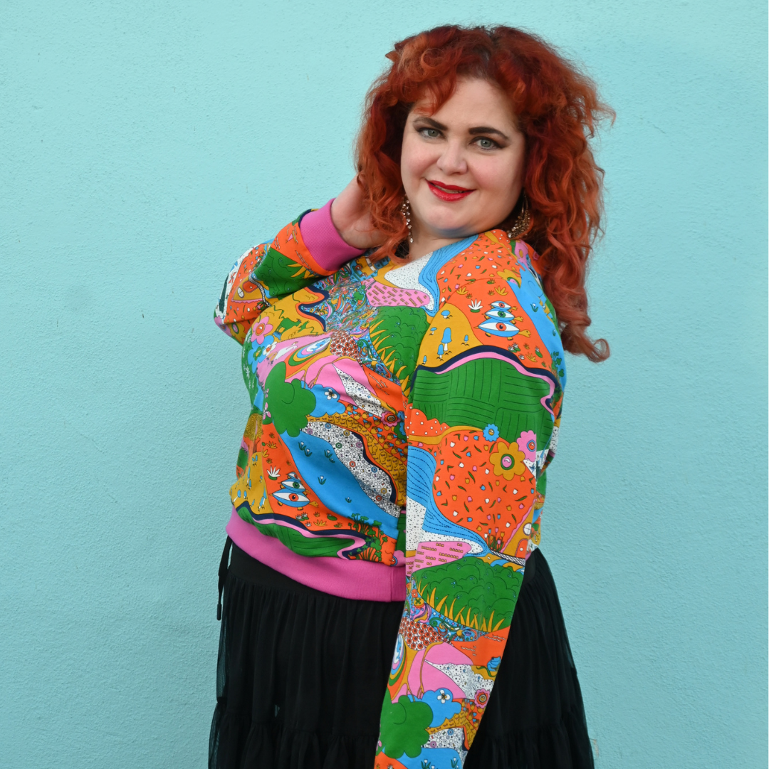 Red-haired model in rainbow animal print sweatshirt in rainbow colors, side view