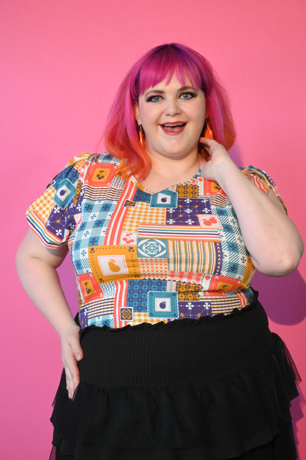 Pink-haired model in shirt printed with patchwork and fruit print