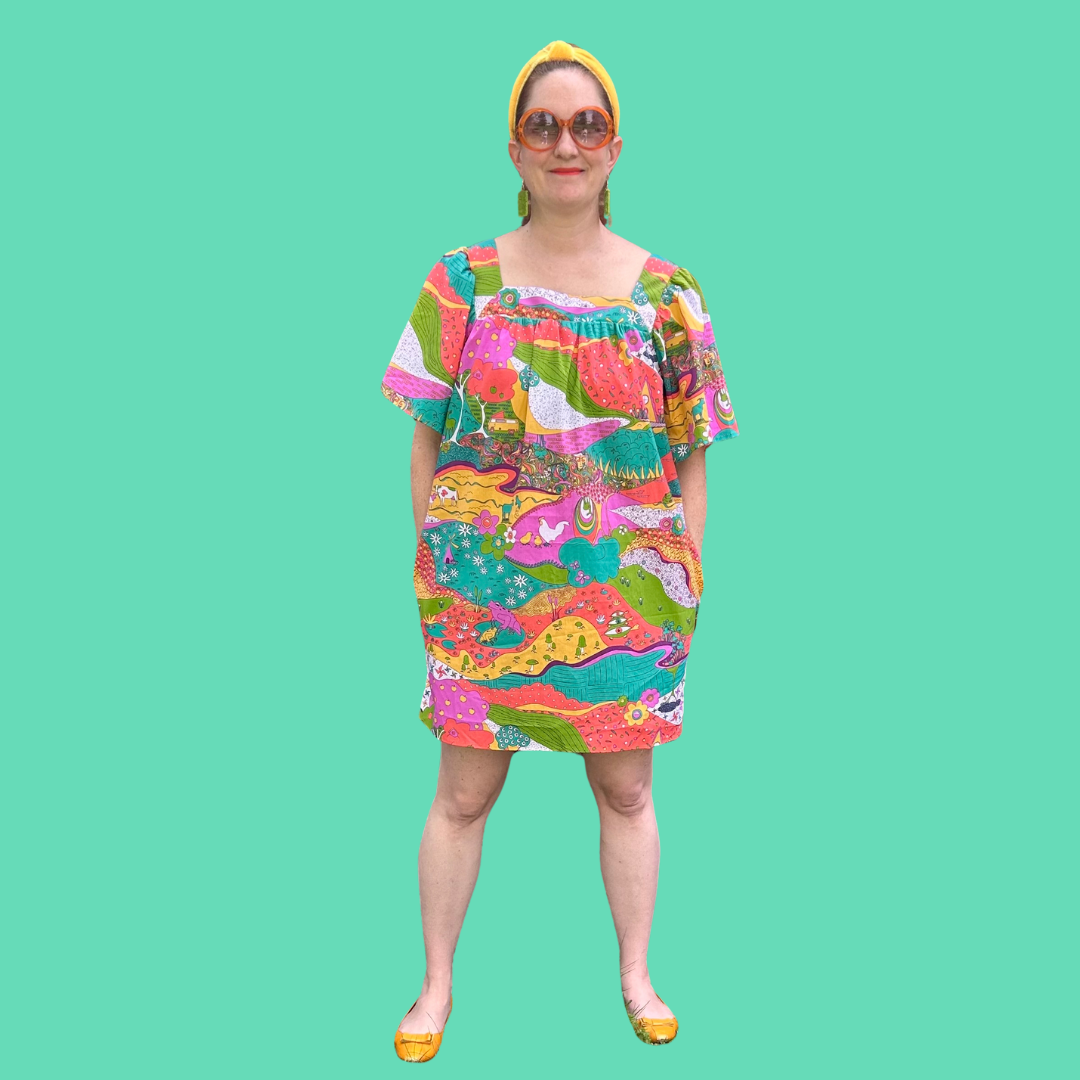 Medium sized model in brightly patterned dress, headband and big sunglasses