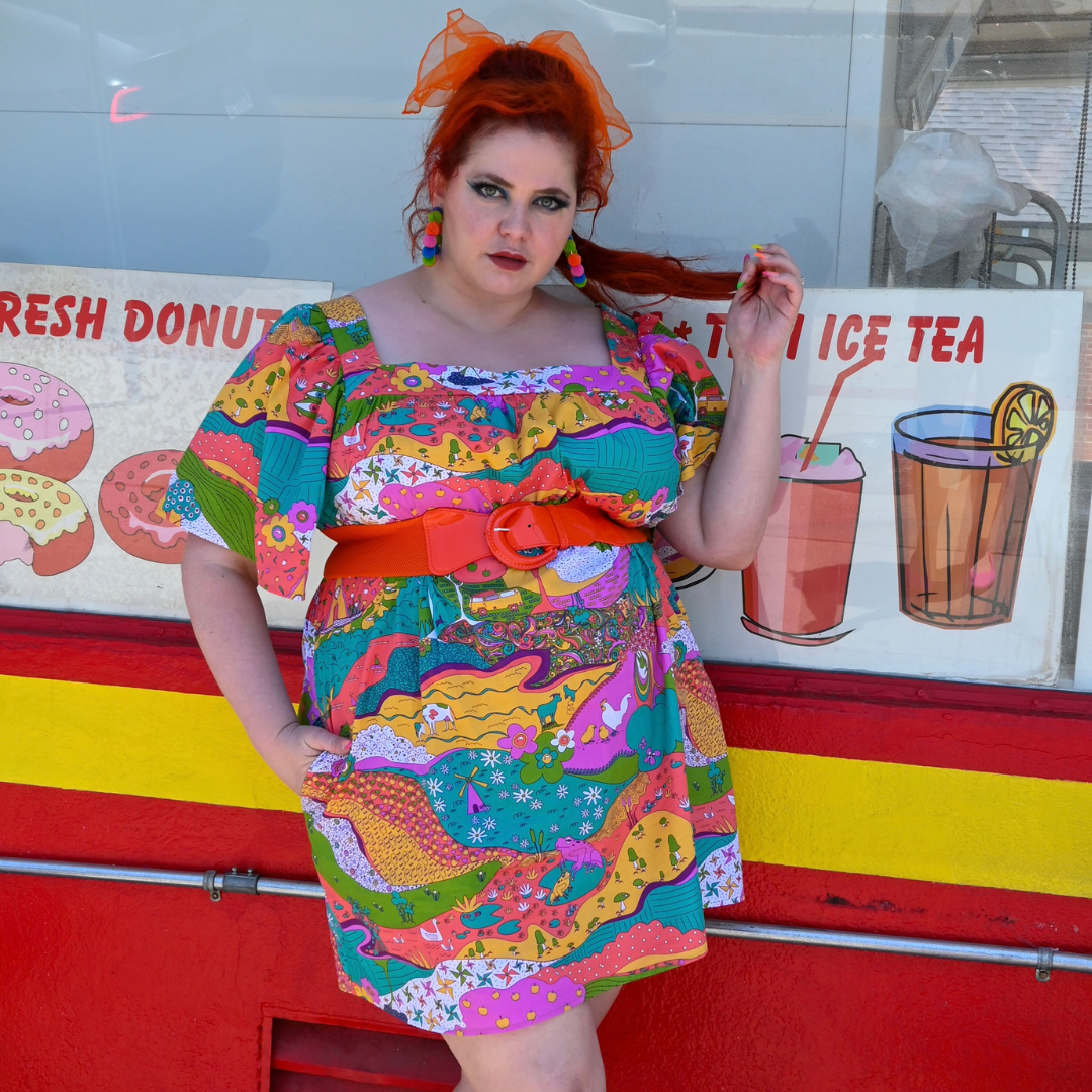 Red-haired model in brightly colored outfit in front of a donut shop