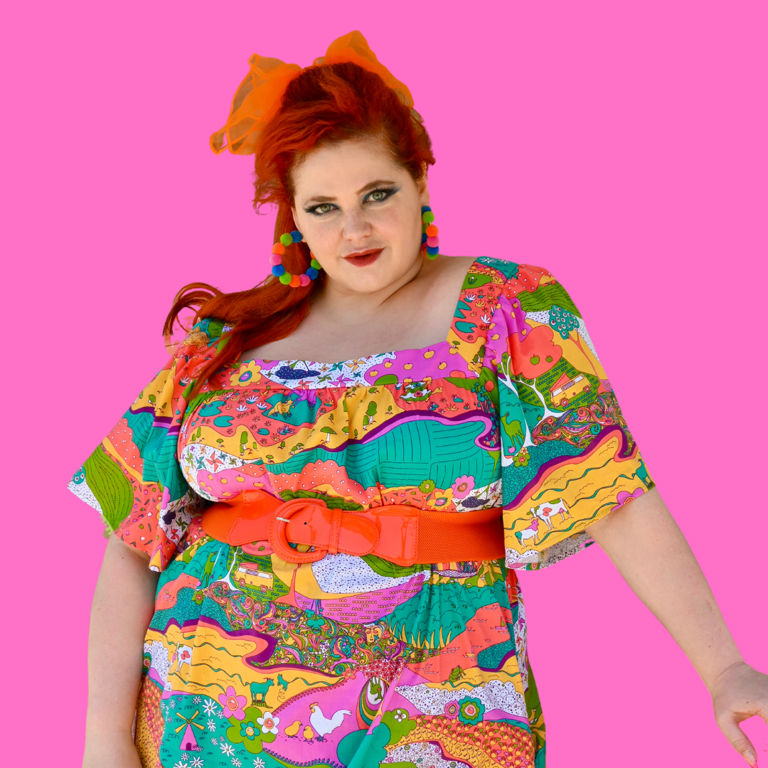 Red-haired model in retro print dress on pink background