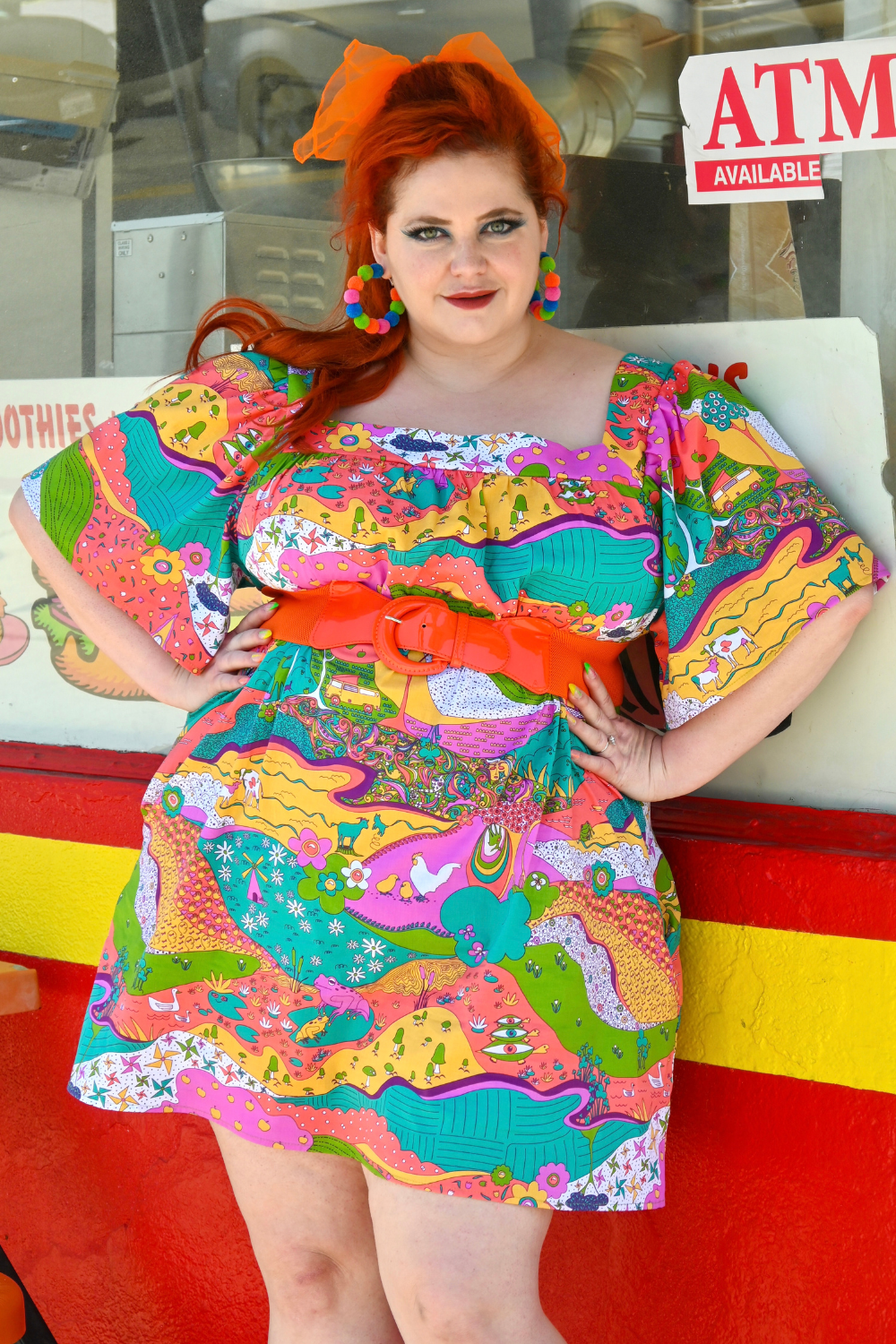 Red-haired model in brightly colored dress with flared sleeves and animal print