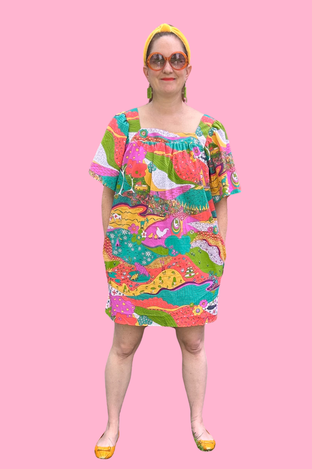 Model in brightly colored dress with animals and trees in bright colors