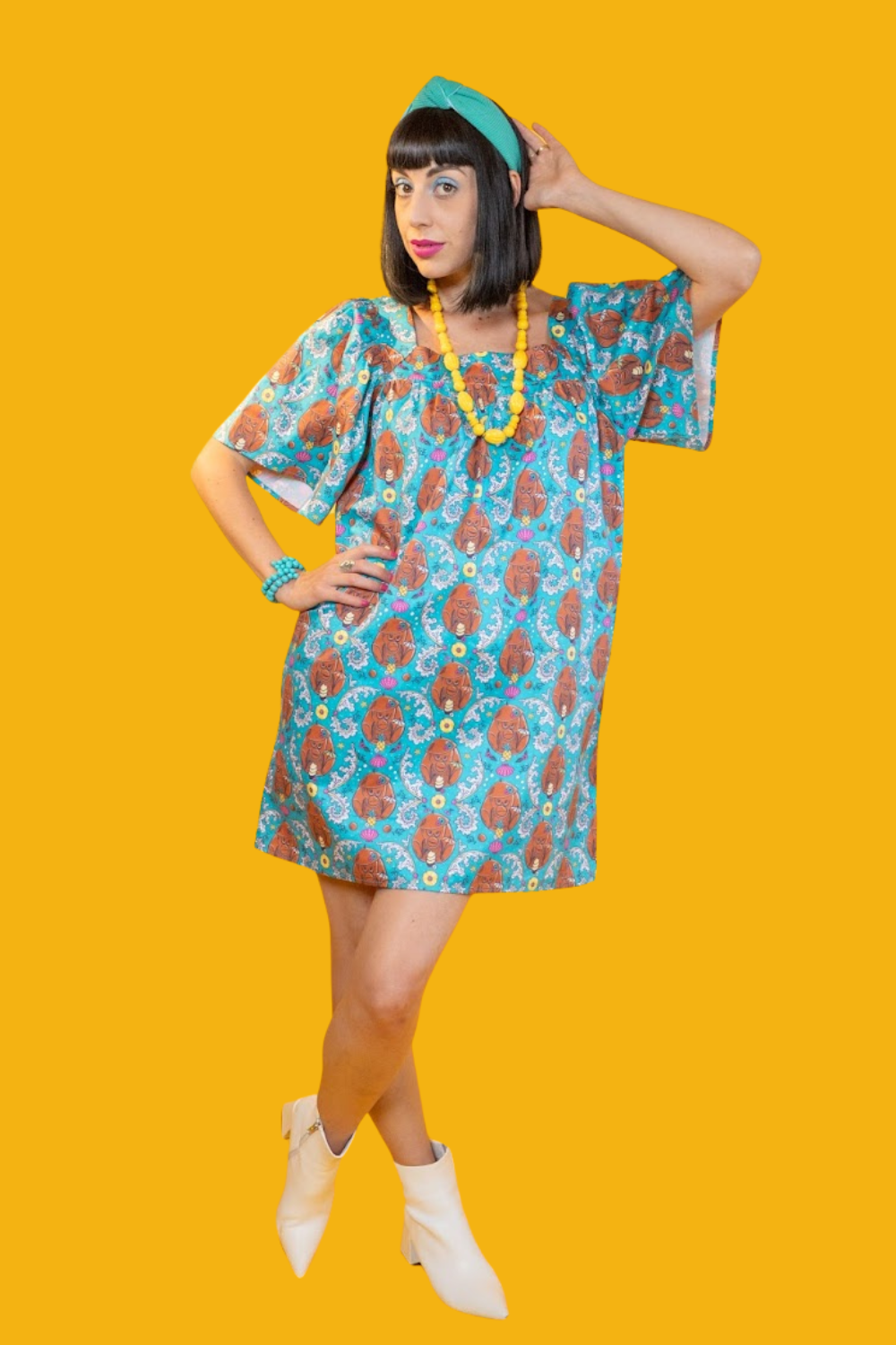 Model in short teal coconut monkey print dress  and fun accessories