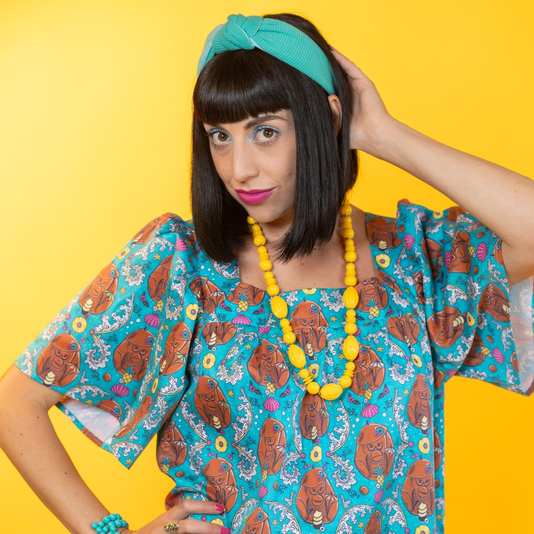 Closeup of model in short teal coconut monkey print dress  and fun accessories