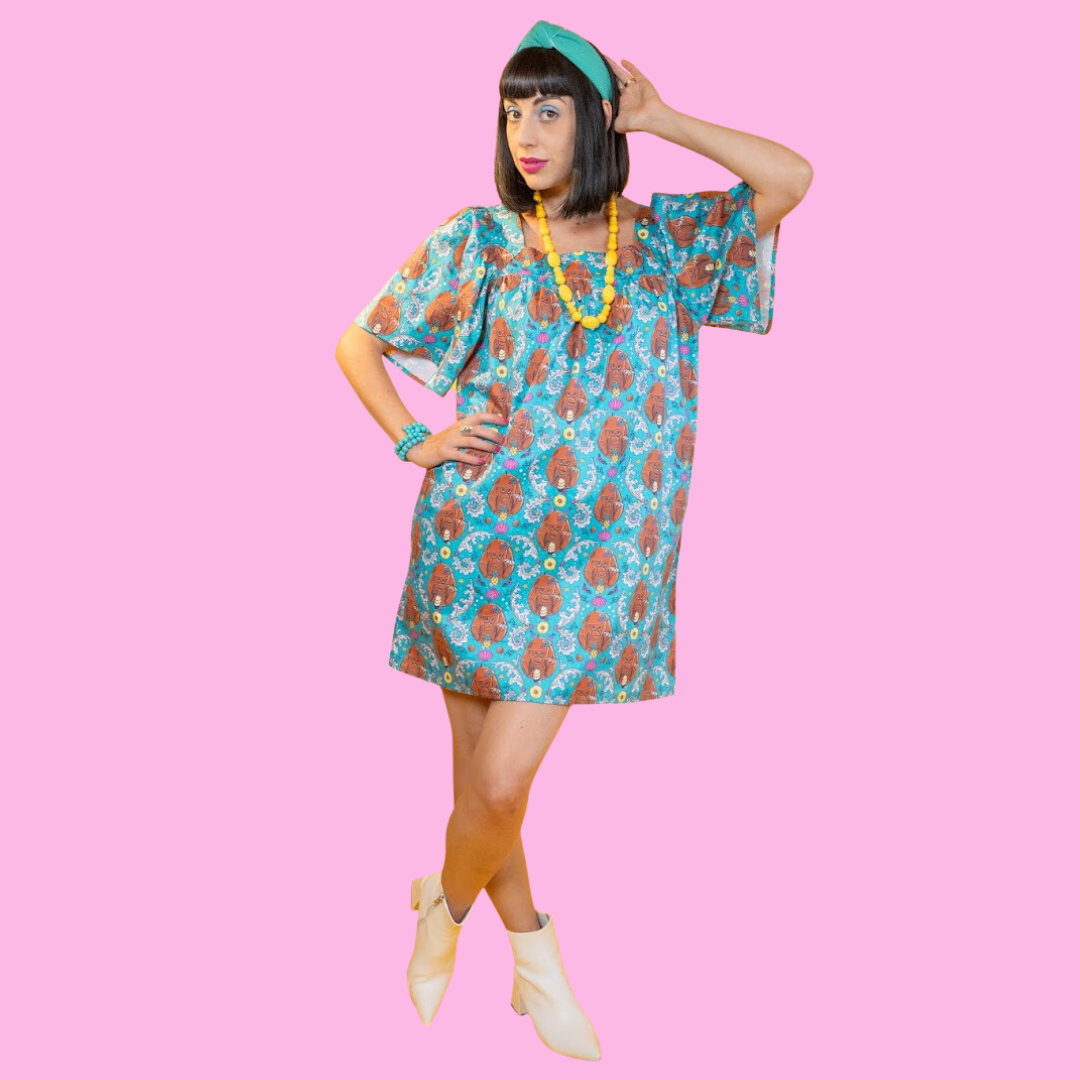 Model posing with hand on hip and wearing coconut monkey print dress in teal with pineapples