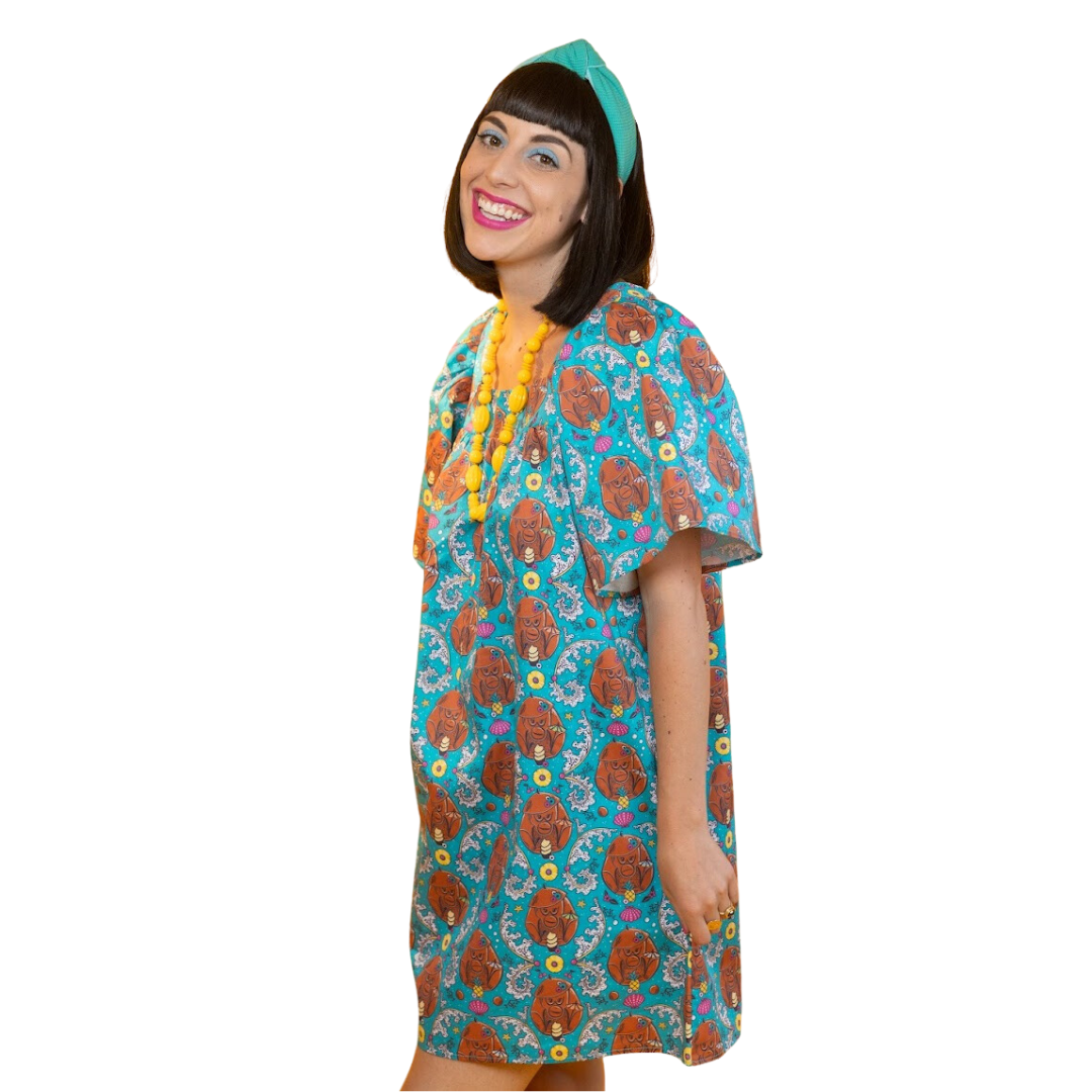 Side view of model in teal tiki monkey and pineapple print minidress