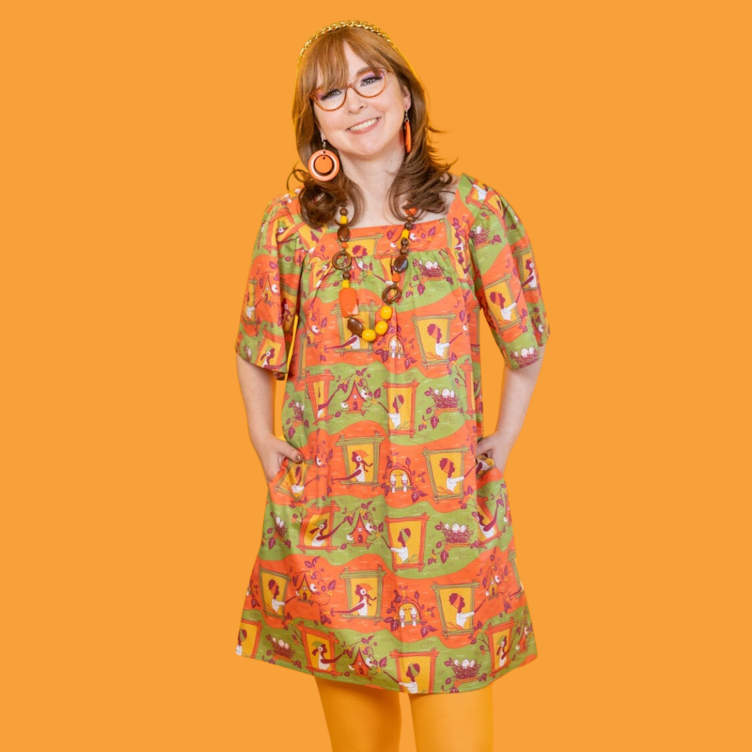 Cute model in glasses wearing orange and green printed dress