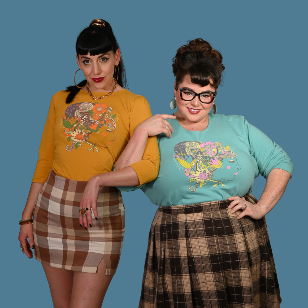 Two women wearing colorful shirts and plaid skirts against a blue background