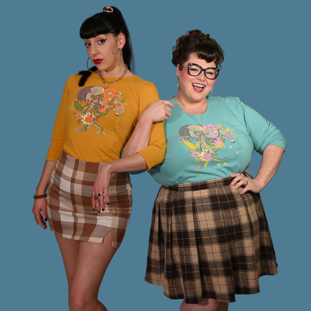 Two women wearing colorful shirts and plaid skirts against a blue background
