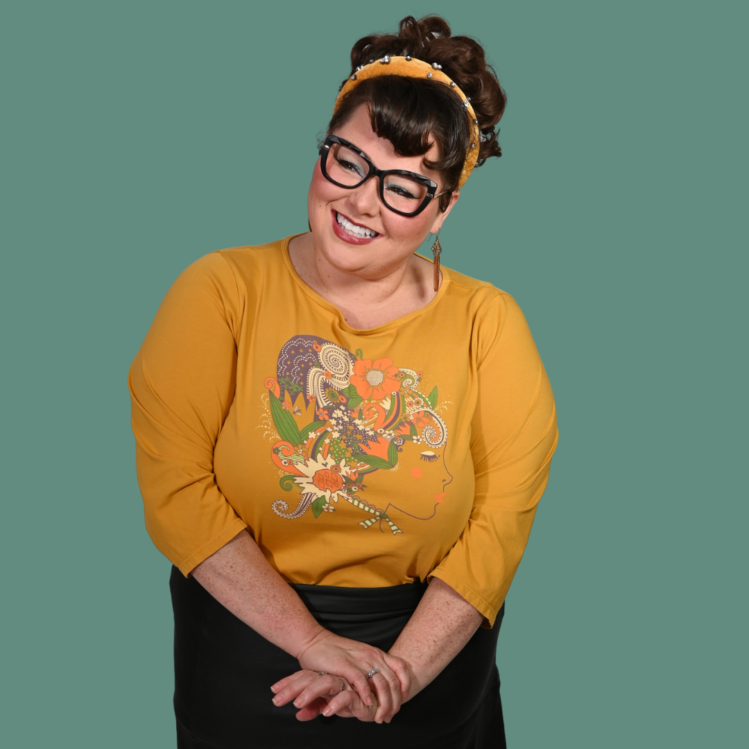 Cute lady in glasses wearing a yellow graphic print shirt with a colorful design on a green background