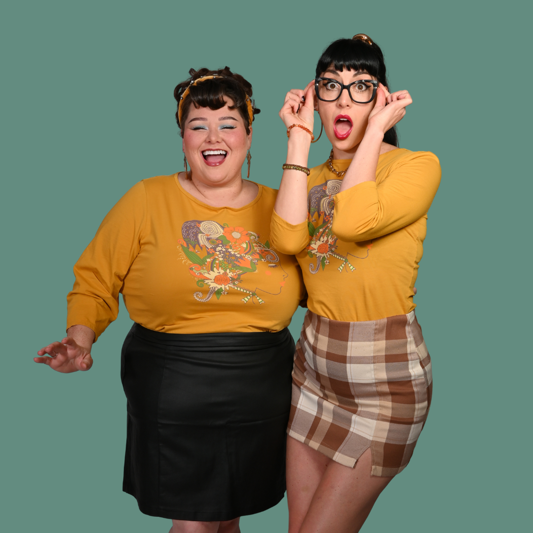 Two women wearing yellow shirts with 60s inspired graphic designs on a green background