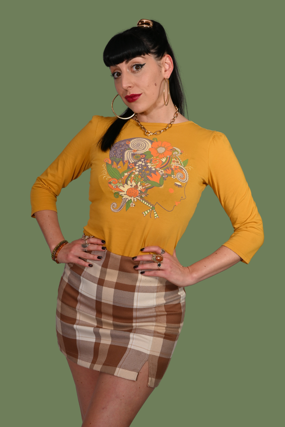 Woman wearing a mustard yellow shirt with a floral design and a plaid skirt on a transparent background
