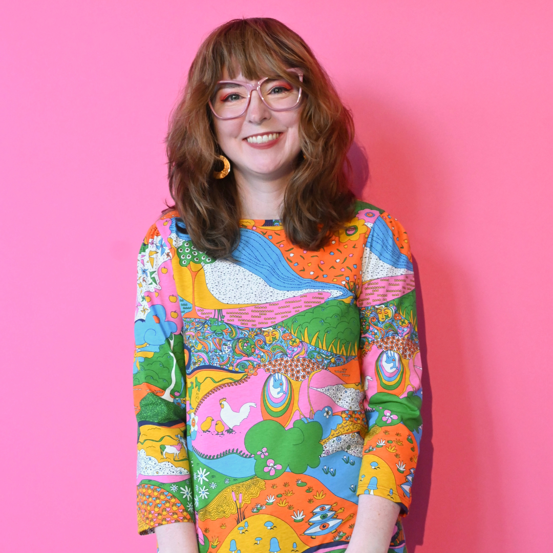 Brown-haired model wearing glasses and rainbow landscape print tee