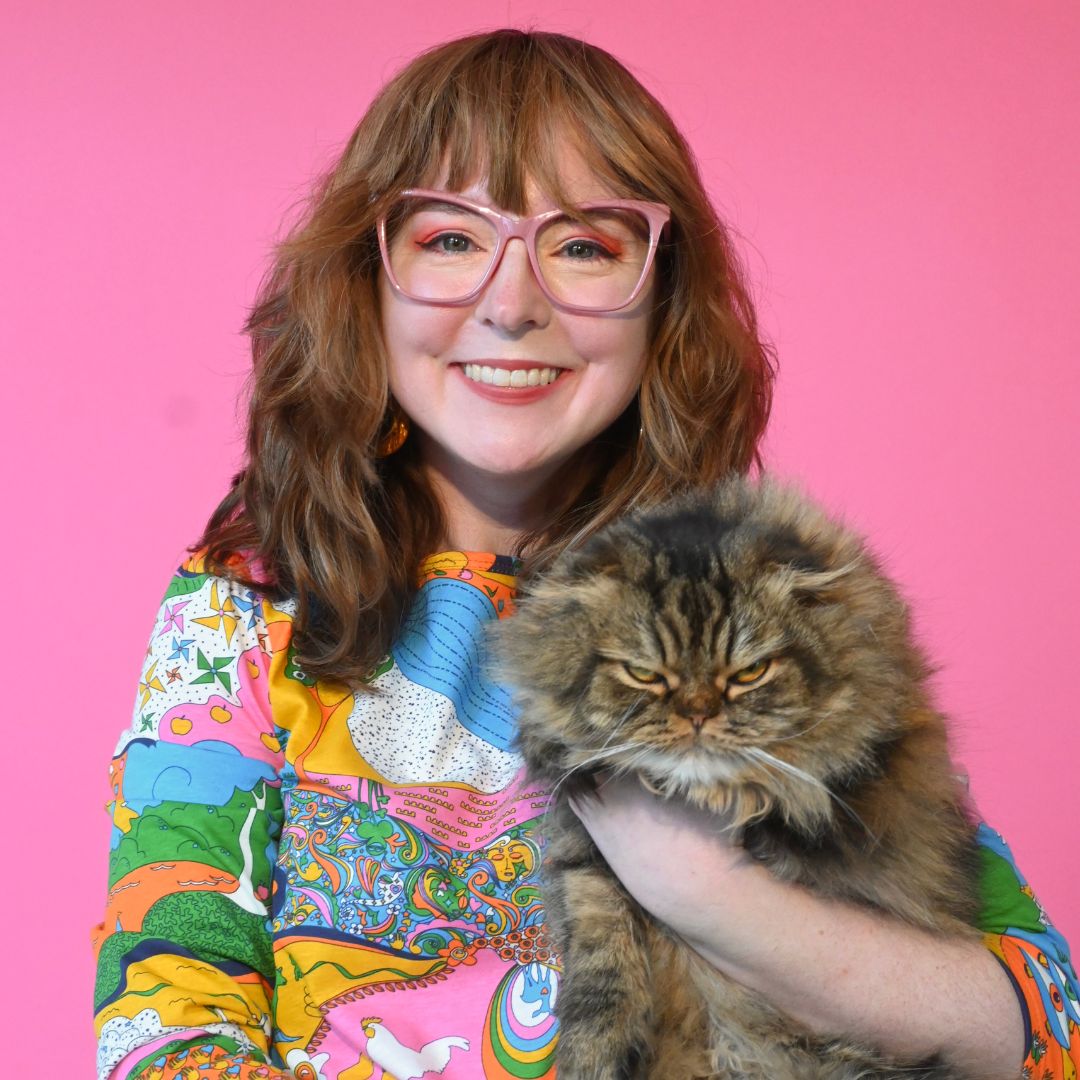 Closeup of girl wearing glasses, holding cat and wearing our rainbow landscape print 3/4 sleeve graphic tee