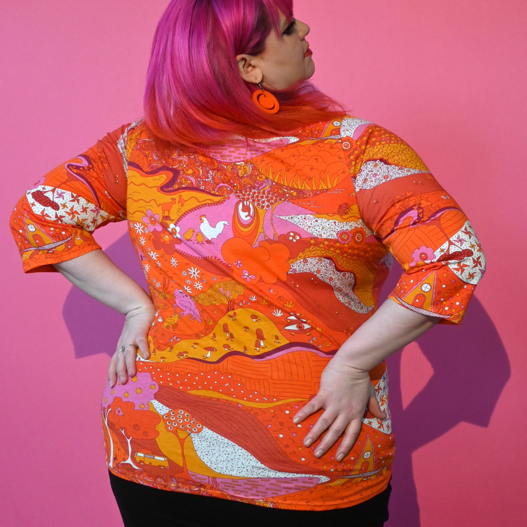 Back view of size 2X graphic landscape print tee in bright orange yellow pink tones