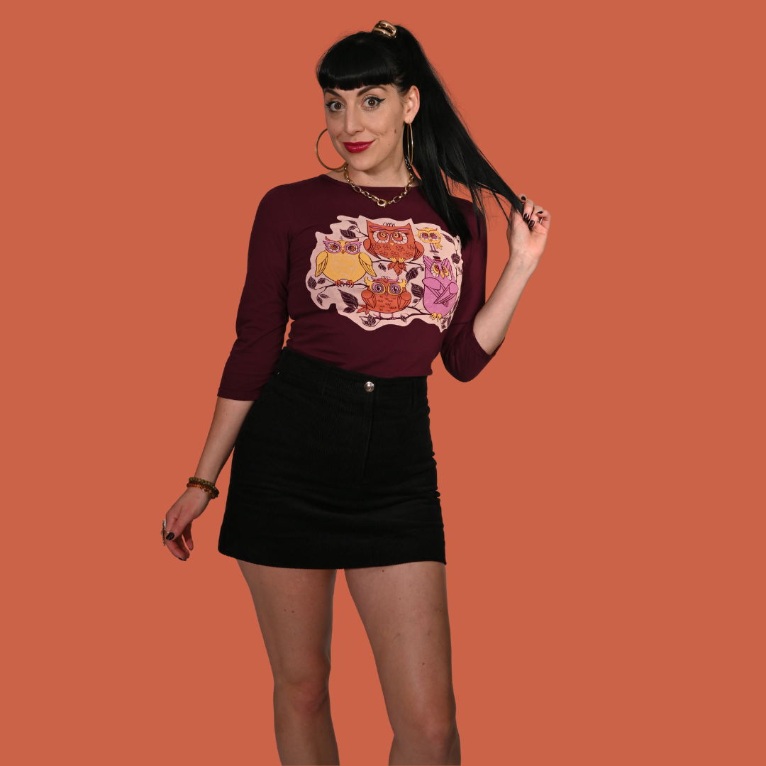 Woman wearing a purple 3/4 tee with a graphic design on an orange background