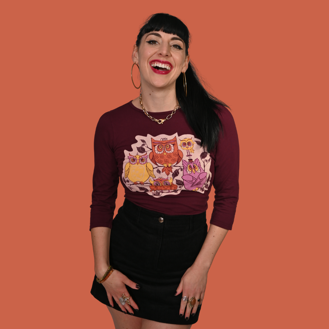 Woman wearing a wine-colored graphic tee with owl design on an orange background