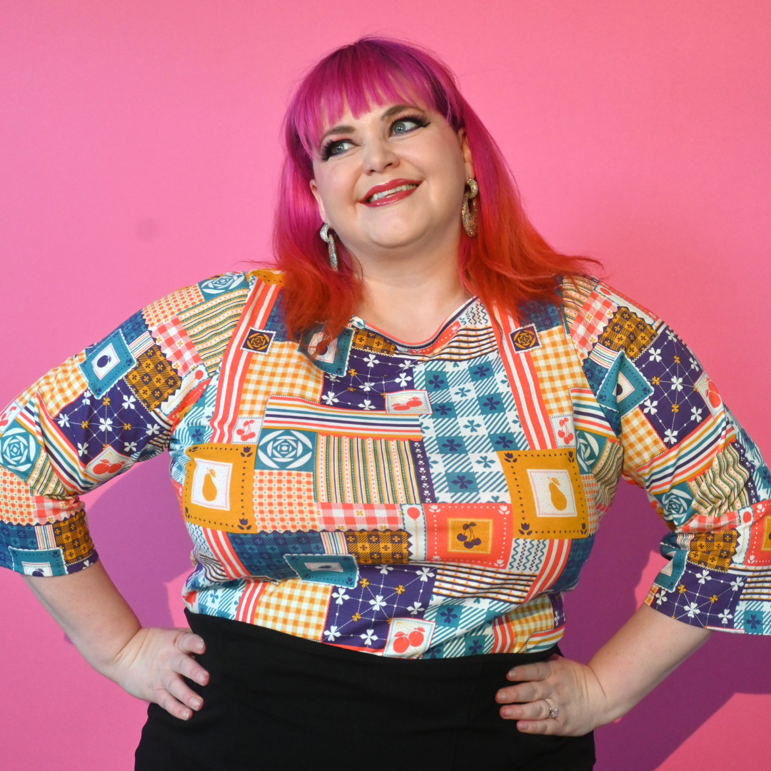 Pink haired model wearing 3/4 sleeve tee featuring colorful patchwork