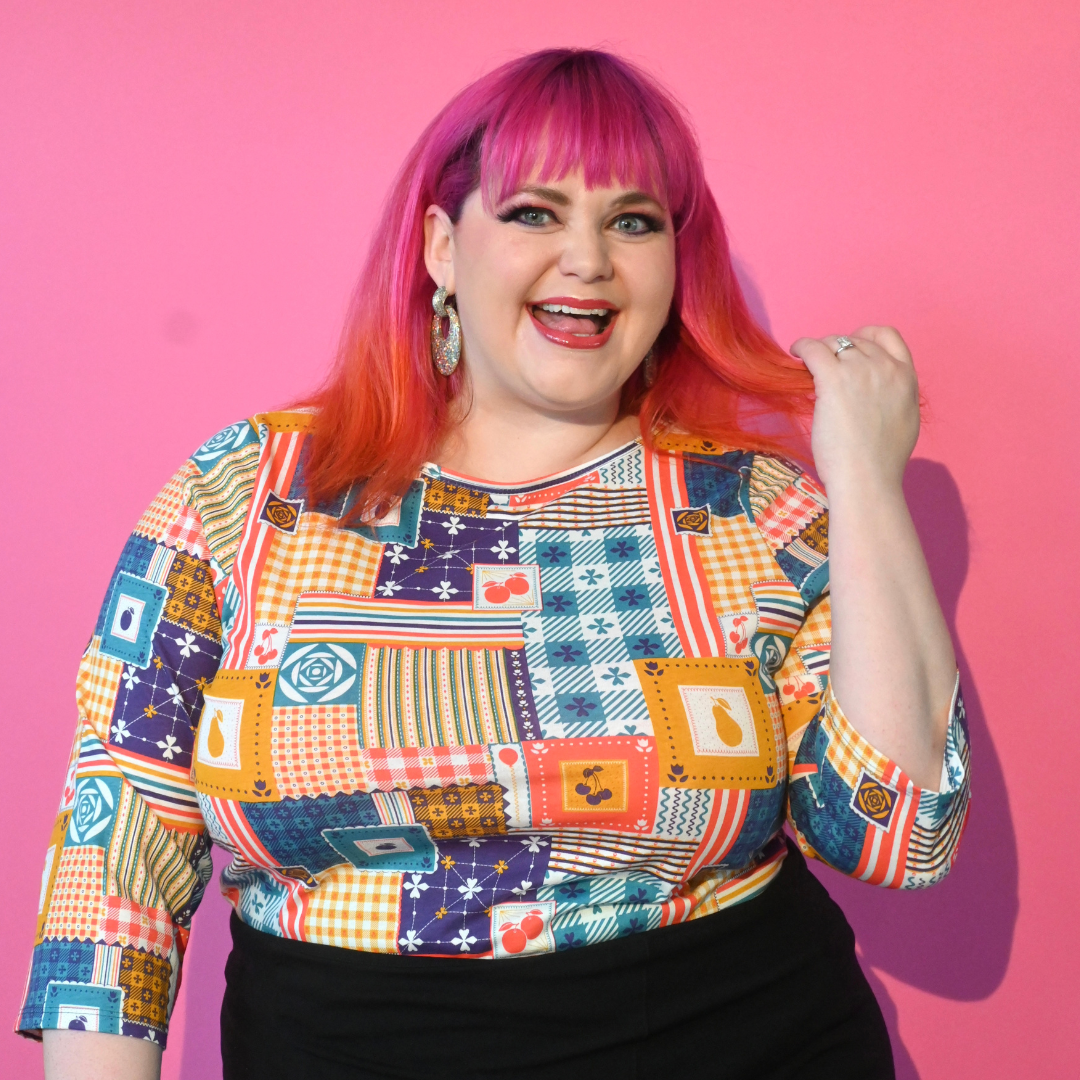 Pink haired model in wearing 3/4 sleeve tee featuring colorful patchwork