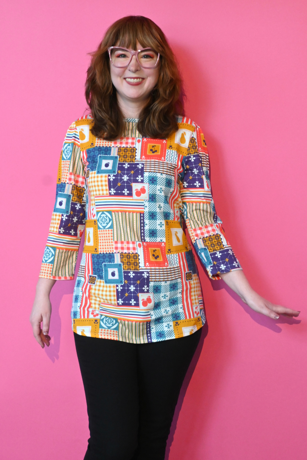 Redhead model in glasses wearing 3/4 sleeve tee featuring colorful patchwork