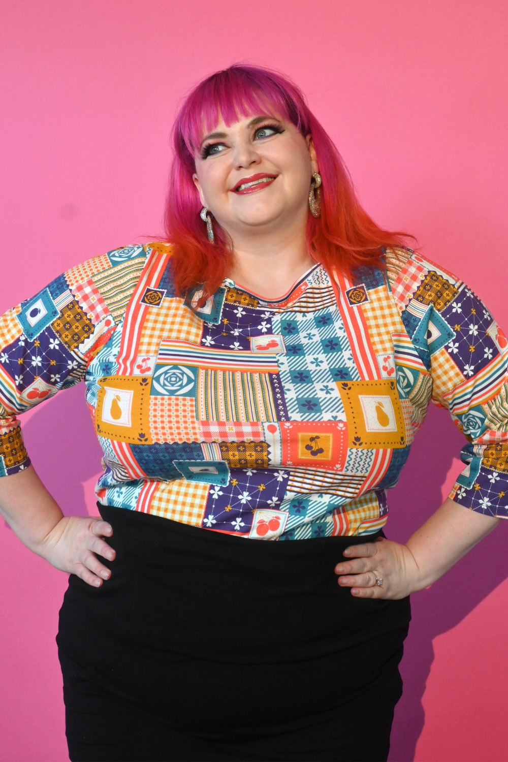 Pink haired model wearing 3/4 sleeve tee featuring colorful patchwork