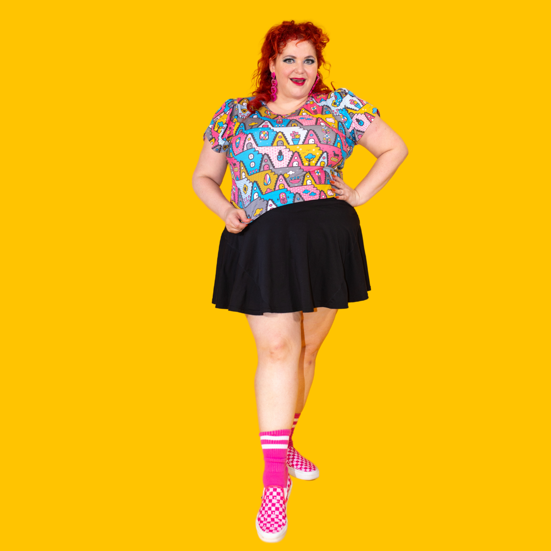 Plus sized red haired model in pastel geometric print tulip sleeved cropped tee, bright socks and shoes