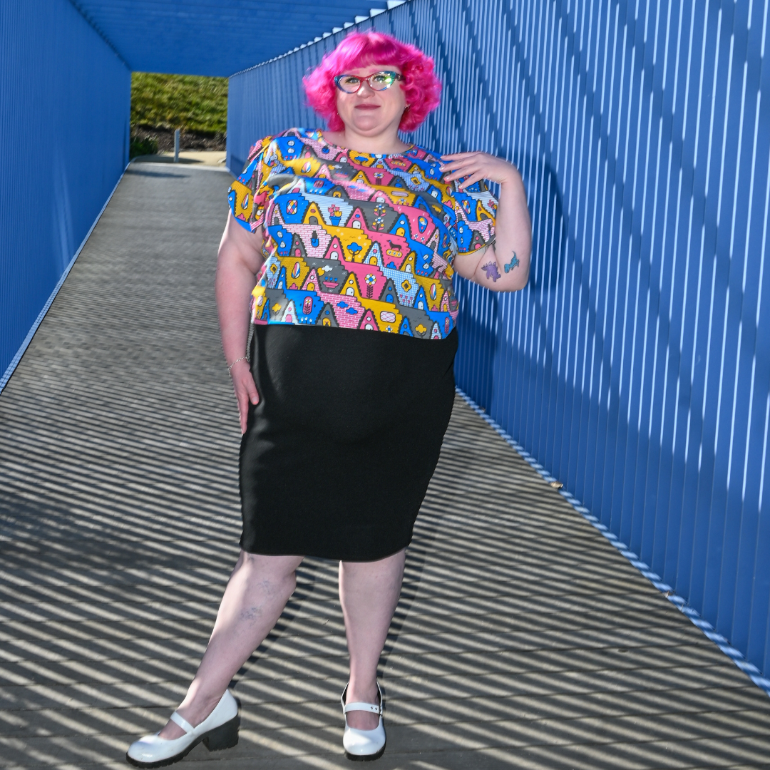 Pink-haired model in geometric a-frame house print tee in blue tunnel