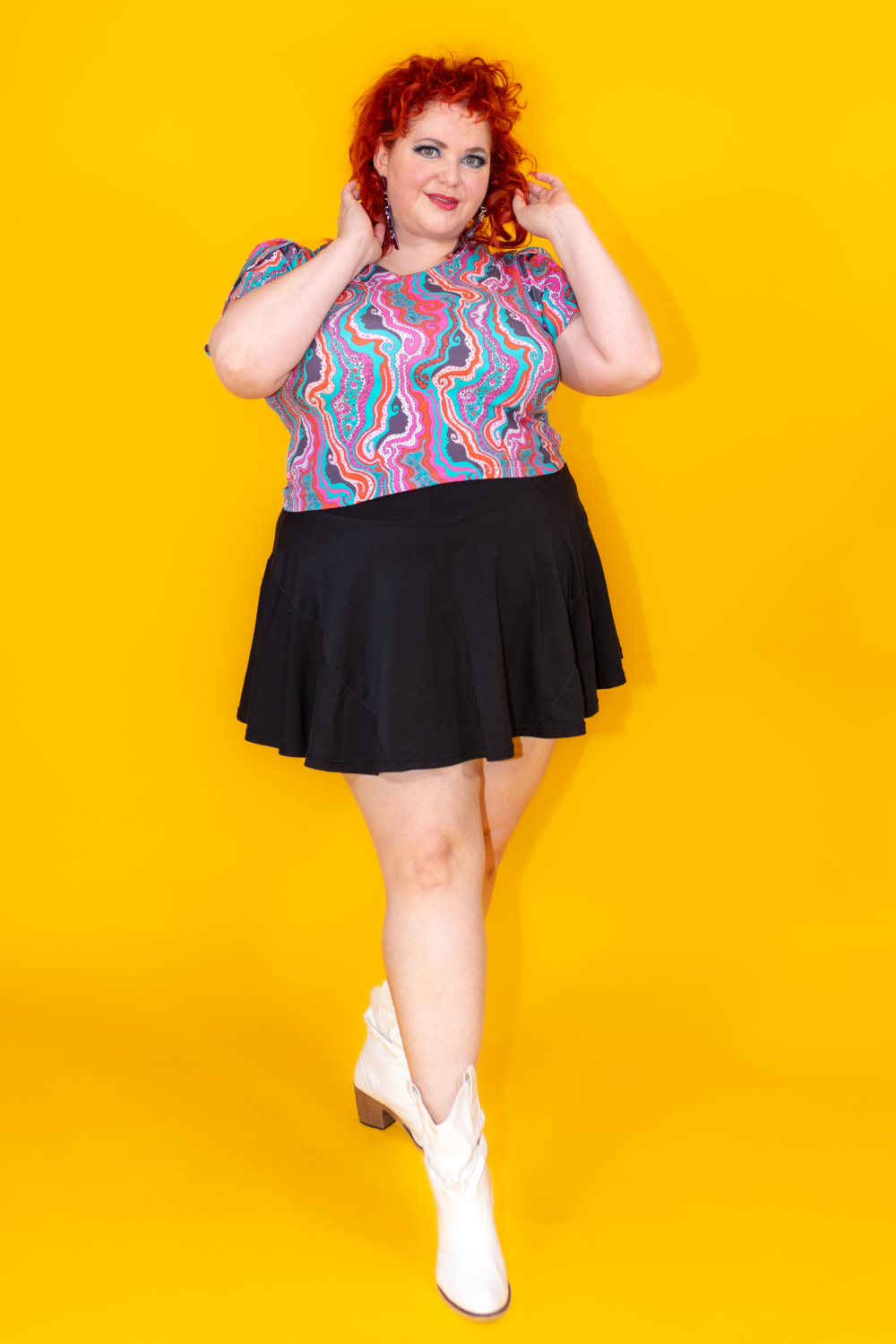 Red haired model wearing a colorful psychedelic tee shirt and black miniskirt