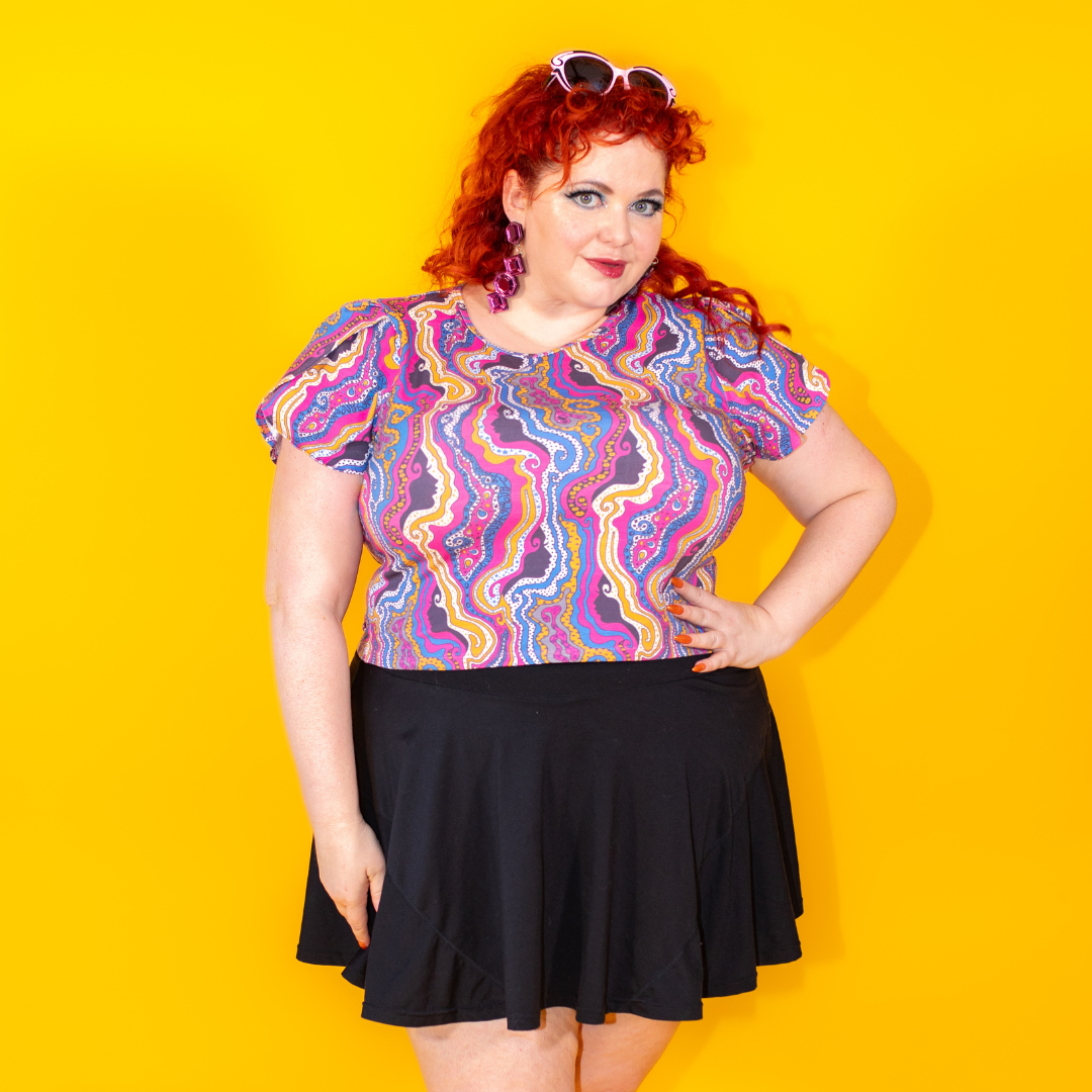 Closeup of red-haired model in psychedelic print cropped tee and black miniskirt