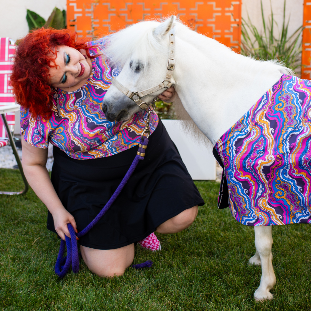 Red haired model and minihorse in matching purple psychedelic print clothing