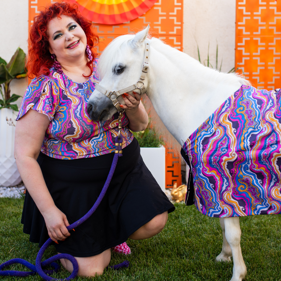 Red haired model and minihorse in matching purple psychedelic print clothing