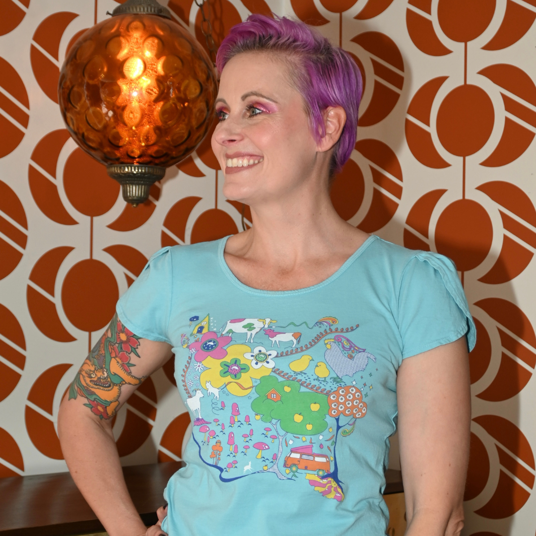 Cute model in light blue graphic tee with animals in front of cool wallpaper