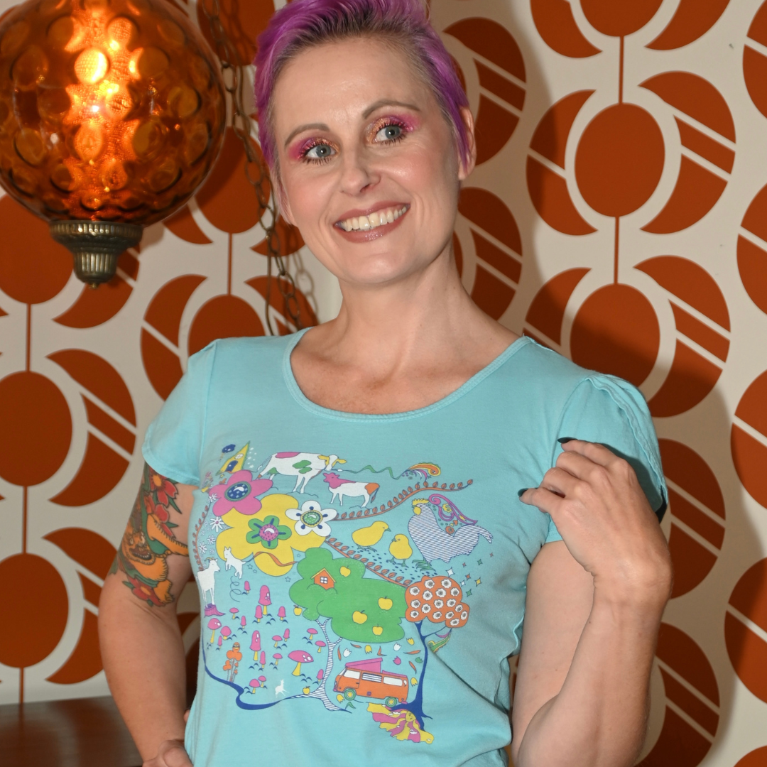 Pink-haired model in light blue graphic tee with animals in front of cool wallpaper