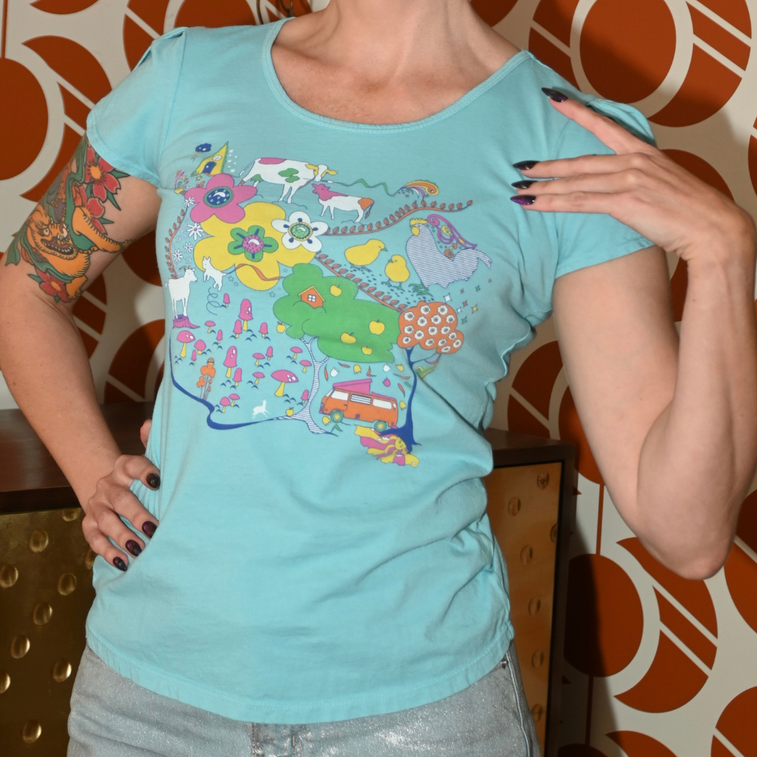 Cute model in light blue graphic tee with animals in front of cool wallpaper