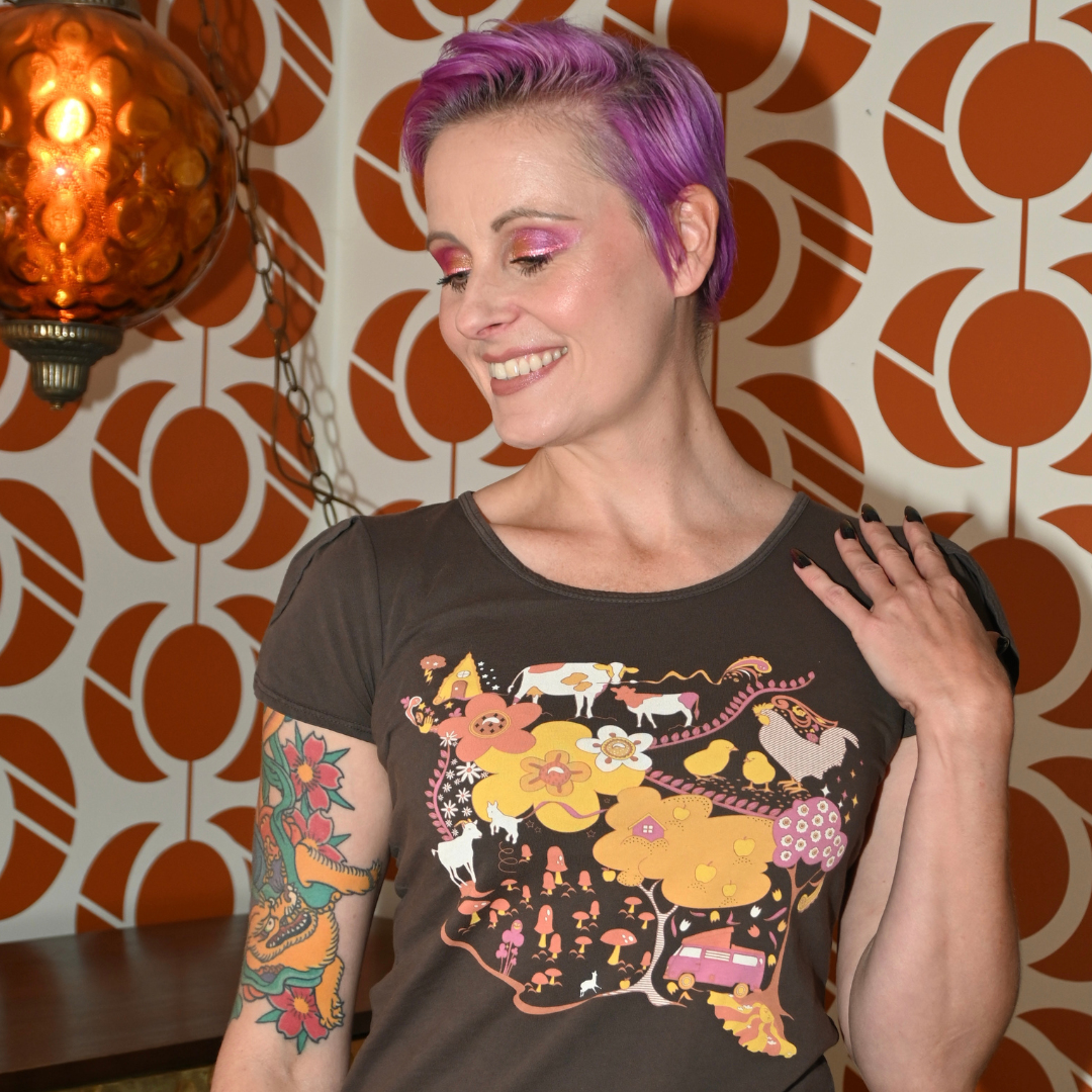 Pink-haired model in brown graphic tee with landscape print