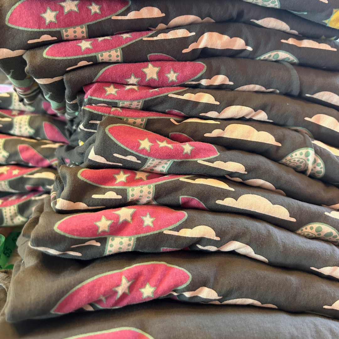 Stack of grey tees with mushrooms, snails and flowers