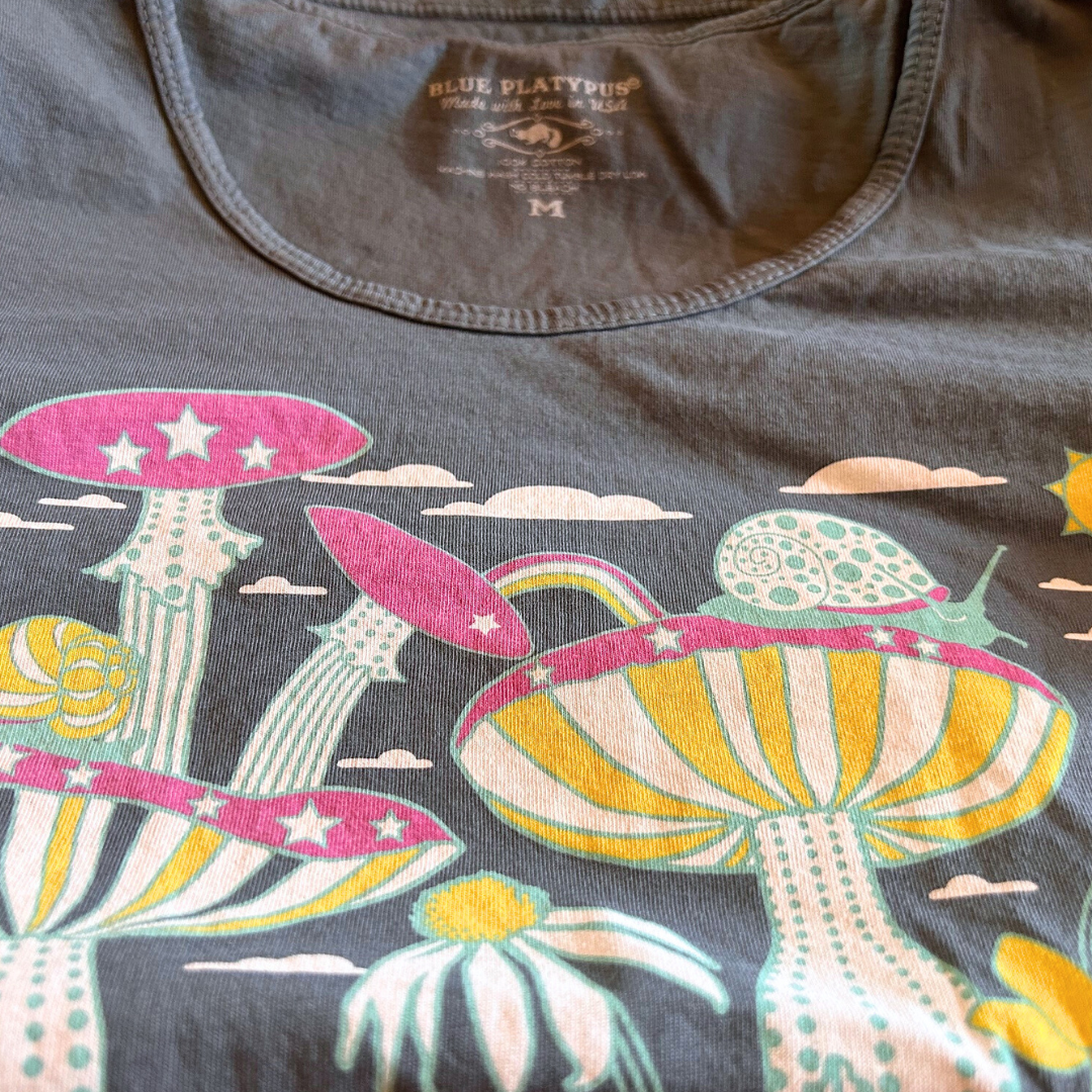 Closeup of grey tee with snails, mushrooms and flowers