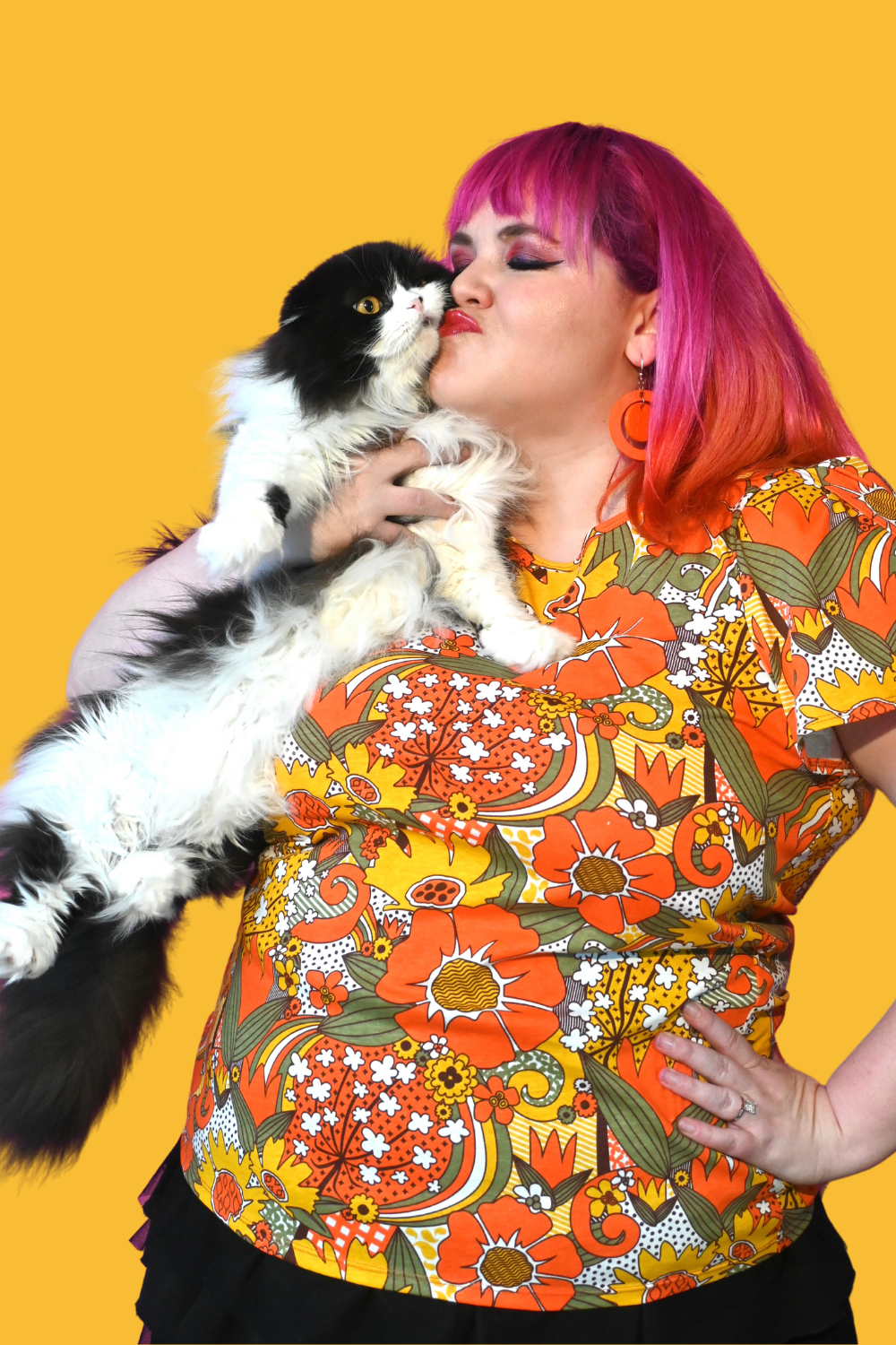 Pink-haired girl with cat wearing bright colored tee with large floral print