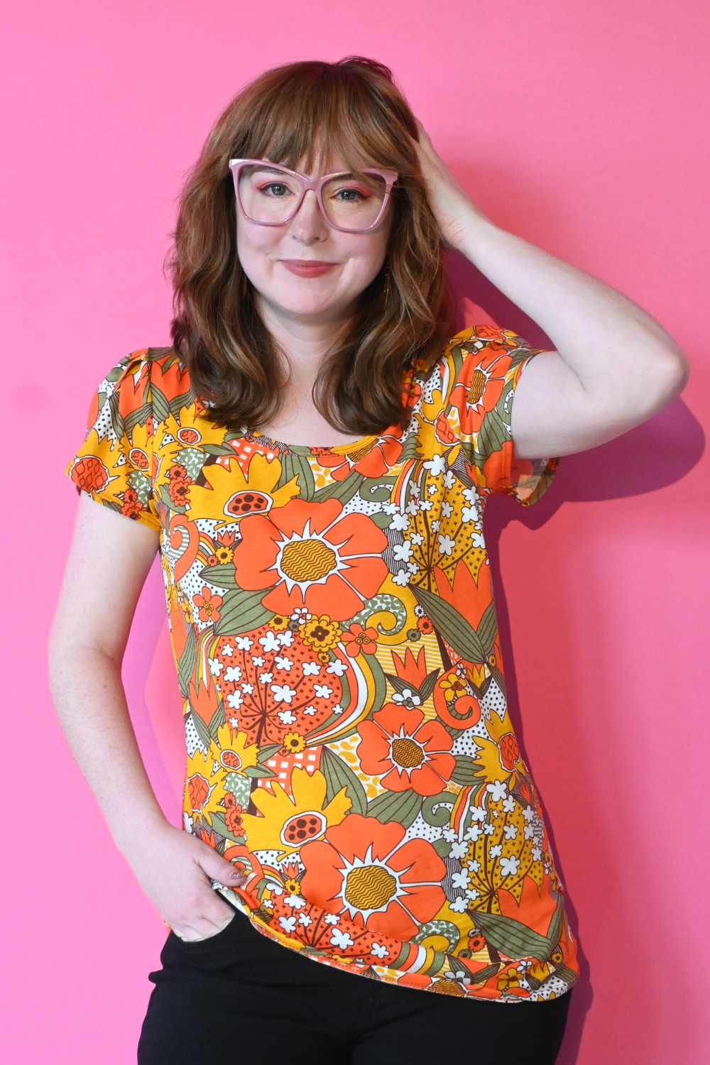 Girl in glasses wearing bright colored tee with large floral print