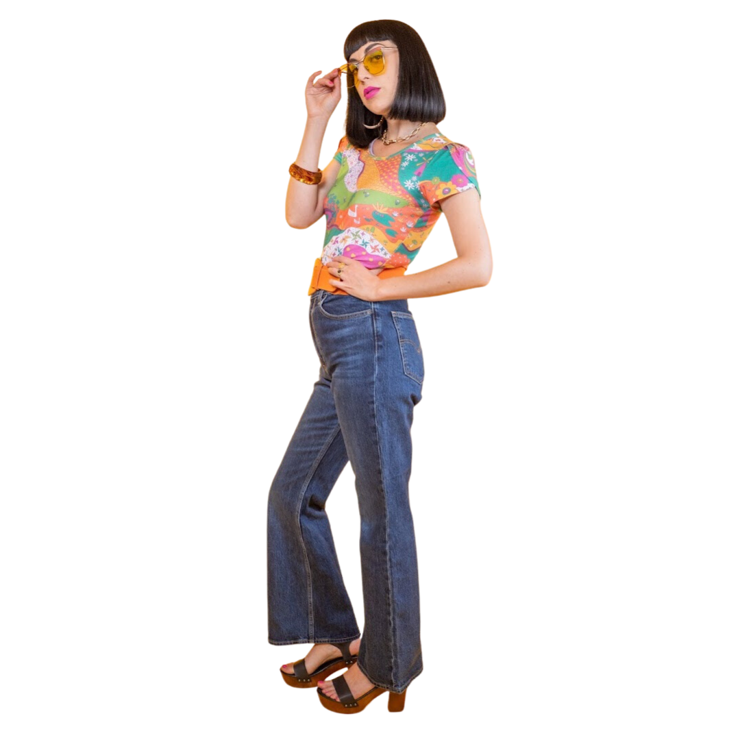 Side view of black-haired model in bright, colorful printed tee, belt and jeans