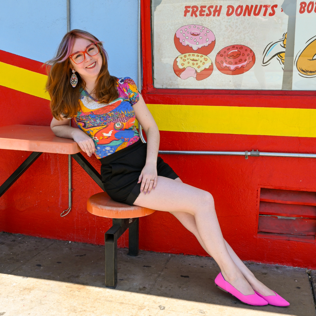 Cute model in glasses and brightly colored shirt, black shorts and pink shoes