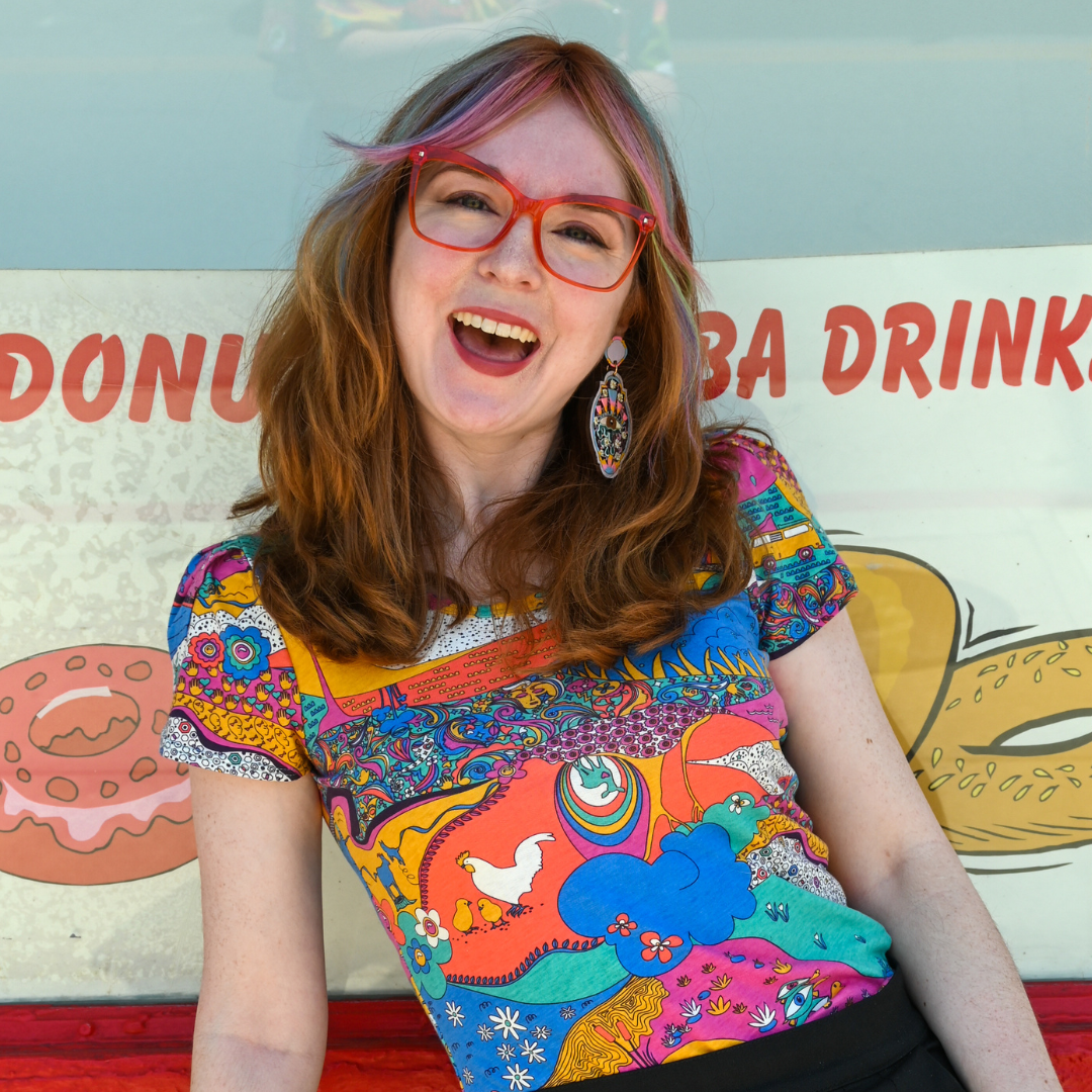 Closeup of happy model in brightly colored shirt in front of a bakery