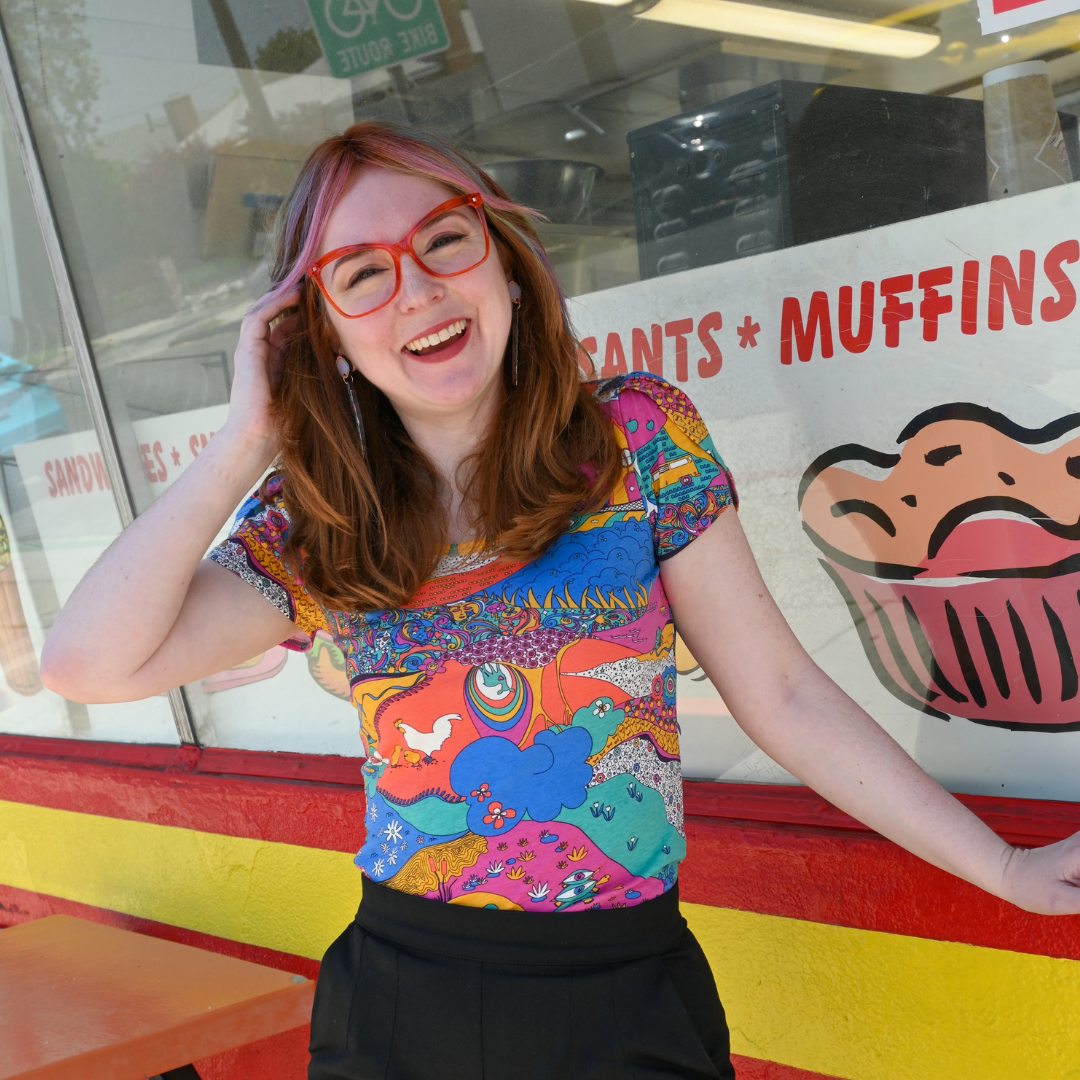 Cute model wearing fun tee with animals and trees in front of a bakery