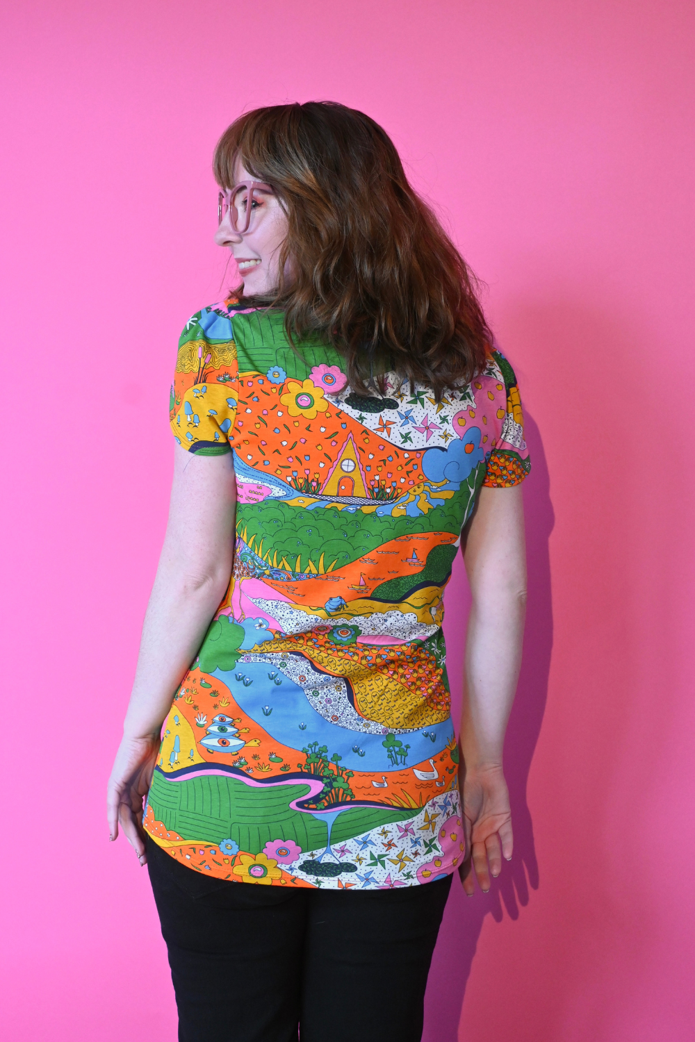Back view of model wearing glasses and shirt with landscape graphic in multicolor