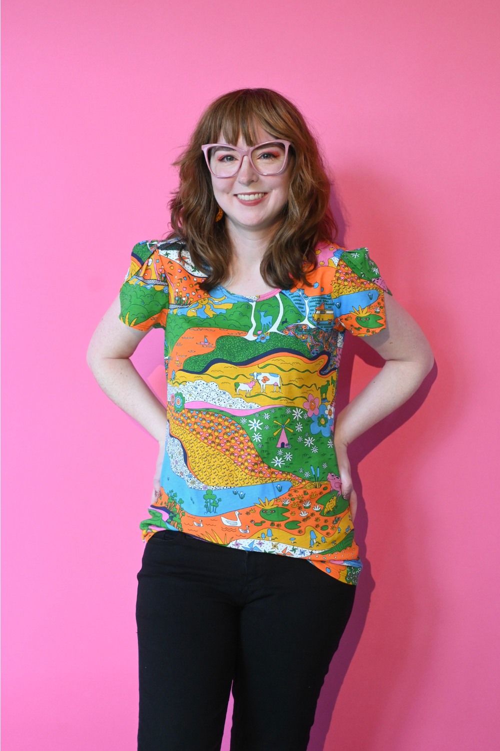 Model with glasses wearing shirt with landscape graphic in multicolor