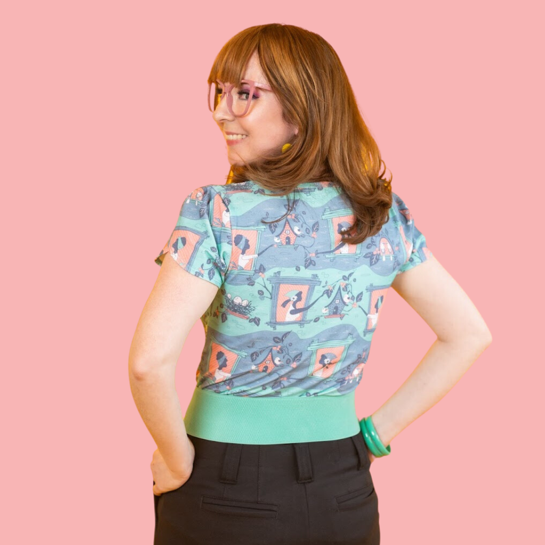 Back view of cute girl in glasses wearing peach and green tee with original allover print of vintage girls