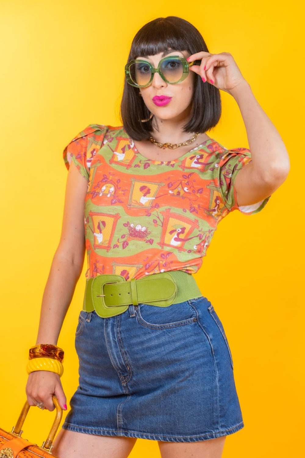 Dark-haired model in orange and green print of girls in windows feeding birds